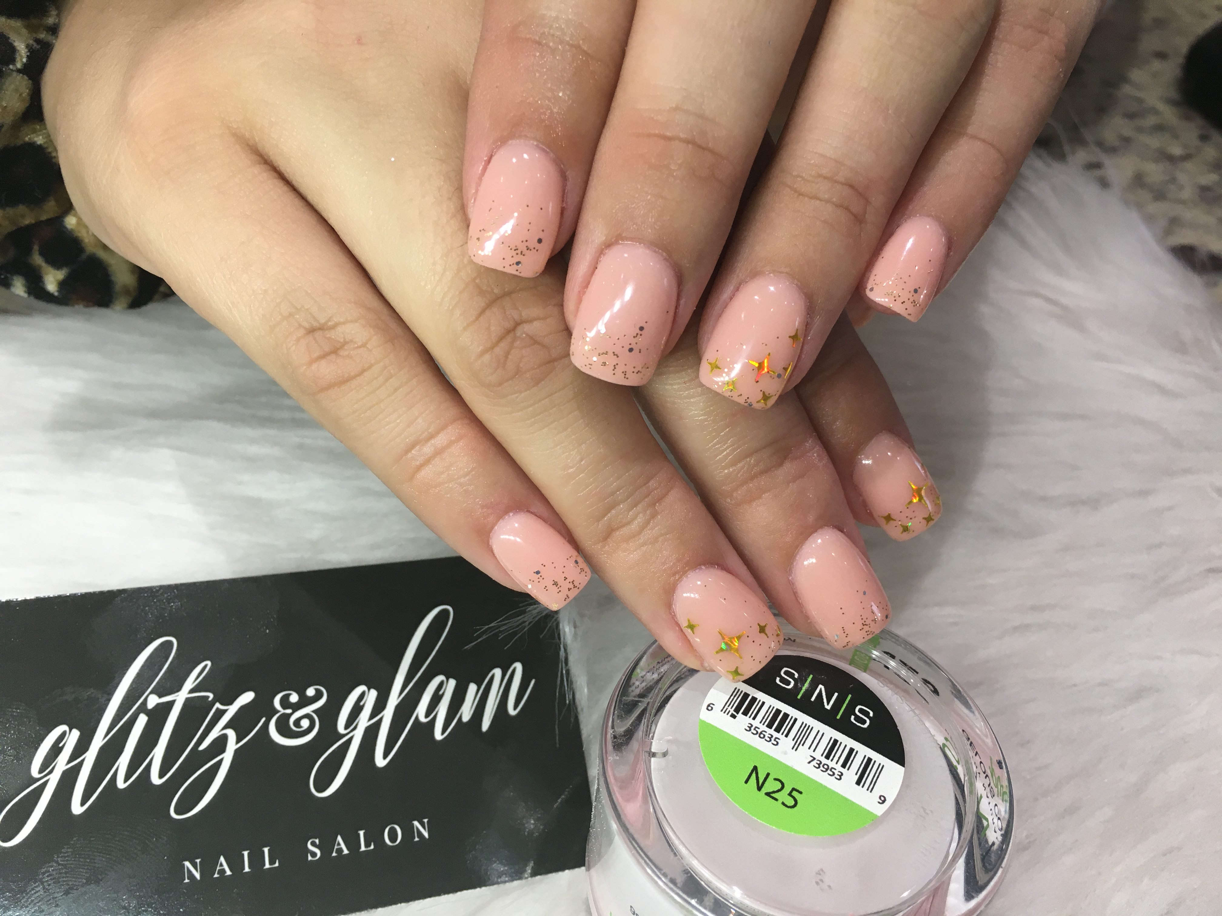 Peach nude nails with gold star art — Glitz & Glam logo card