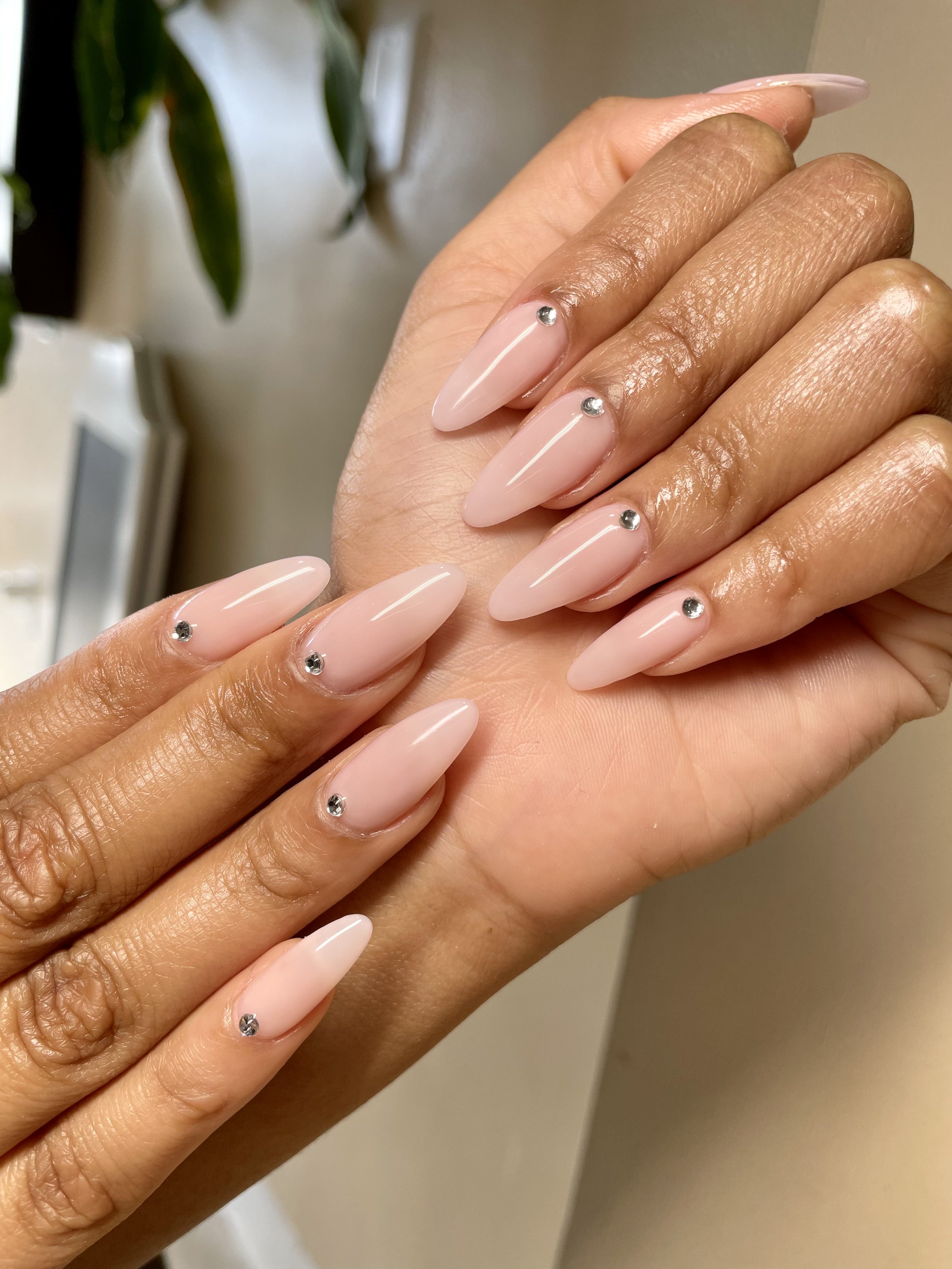 Nude pink almond nails with diamond gem accents
